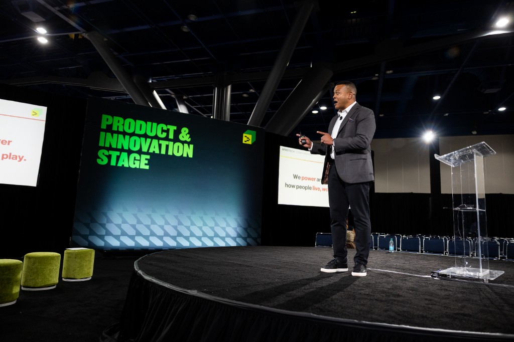 Speaker in a grey suit presenting on the Product and Innovation Stage at AfroTech